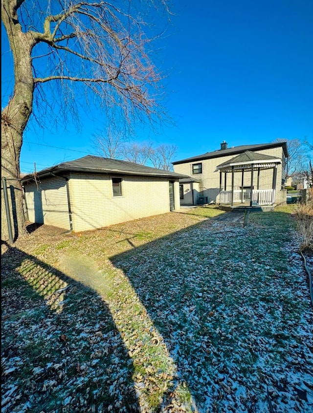 rear view of property featuring a gazebo and a yard