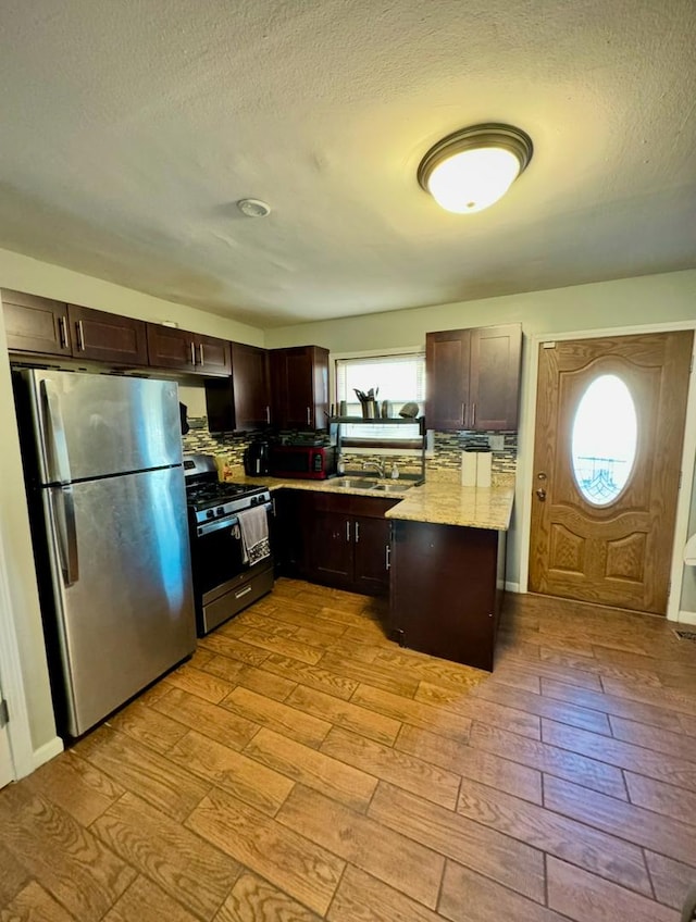 kitchen featuring appliances with stainless steel finishes, light hardwood / wood-style flooring, dark brown cabinets, and sink