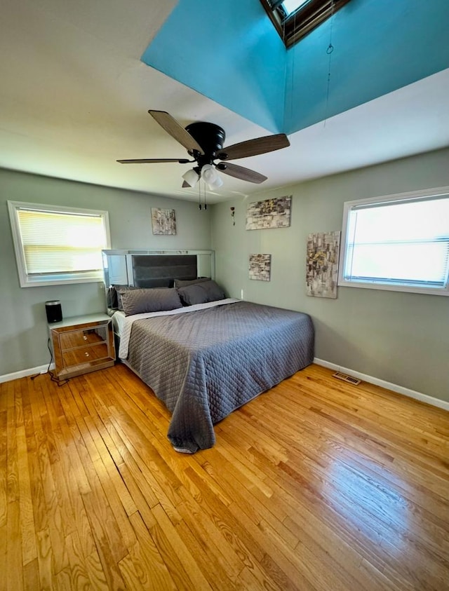 bedroom with ceiling fan, light hardwood / wood-style floors, and multiple windows