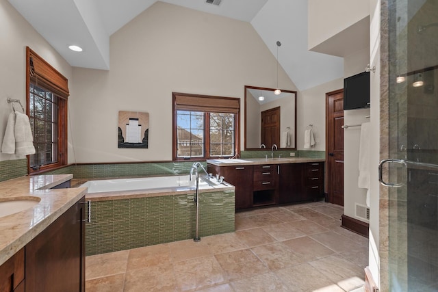 bathroom featuring independent shower and bath, high vaulted ceiling, and vanity