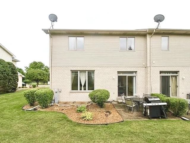 back of property with a lawn and a patio area