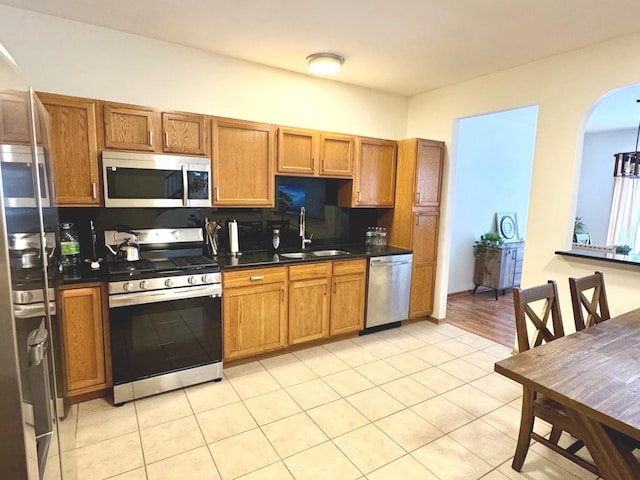 kitchen with tasteful backsplash, sink, light tile patterned flooring, and appliances with stainless steel finishes