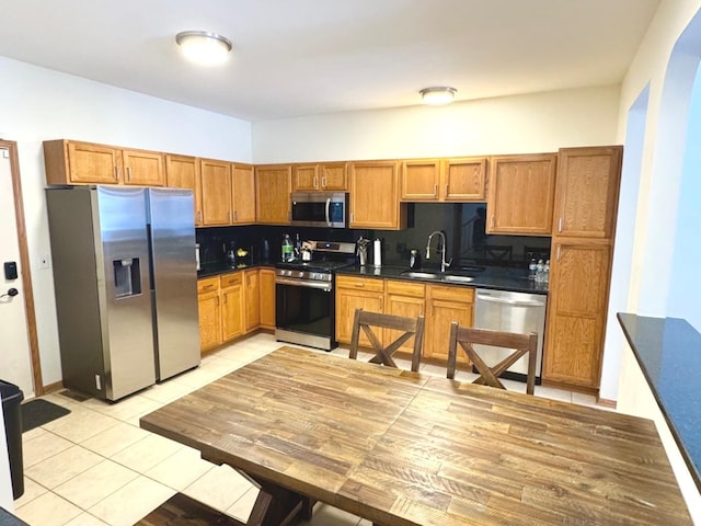 kitchen with decorative backsplash, light tile patterned floors, stainless steel appliances, and sink