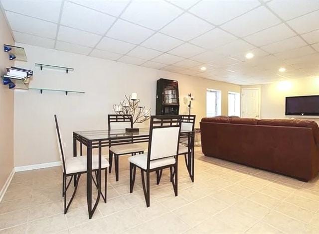 dining area featuring tile patterned floors and a drop ceiling