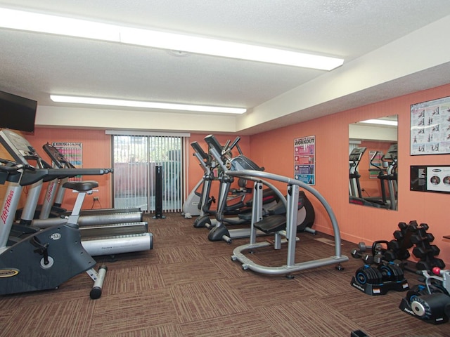 gym featuring a textured ceiling and dark carpet