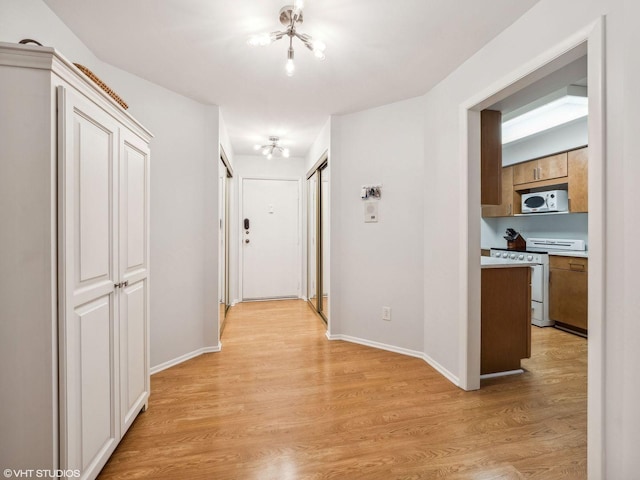 corridor with light hardwood / wood-style flooring and a notable chandelier