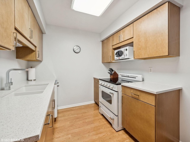 kitchen featuring electric range, sink, light stone counters, and light wood-type flooring