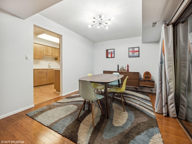 dining space with light wood-type flooring and a notable chandelier