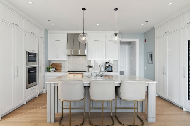 kitchen with white cabinetry and an island with sink