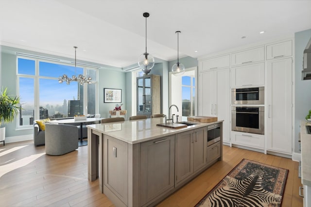 kitchen featuring stainless steel appliances, a kitchen island with sink, sink, and hanging light fixtures