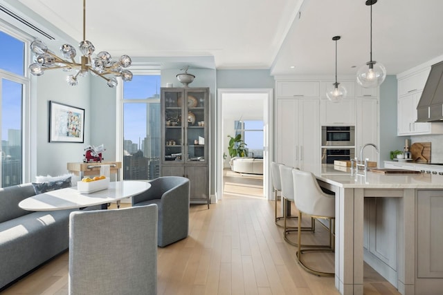 kitchen with an inviting chandelier, light stone counters, light hardwood / wood-style flooring, double oven, and pendant lighting