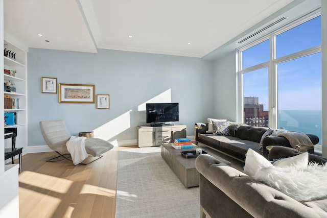 living room with built in shelves, light hardwood / wood-style flooring, and ornamental molding