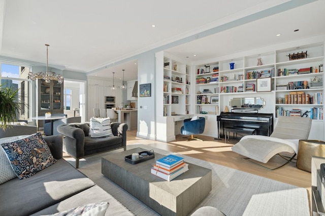 living room with built in shelves, crown molding, light hardwood / wood-style flooring, and a notable chandelier