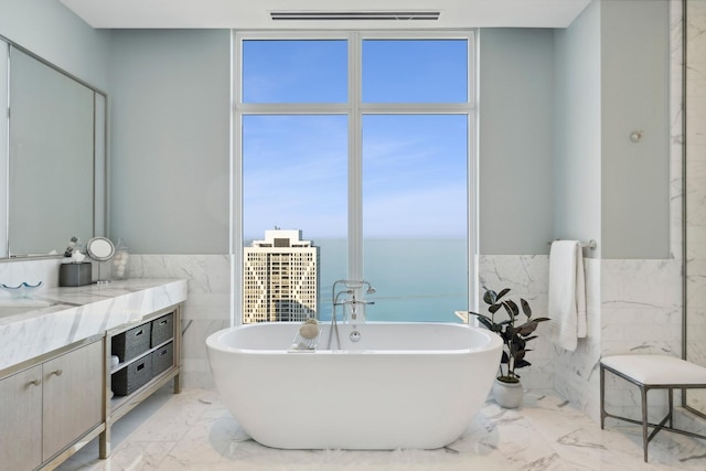 bathroom with vanity, a washtub, a water view, and tile walls