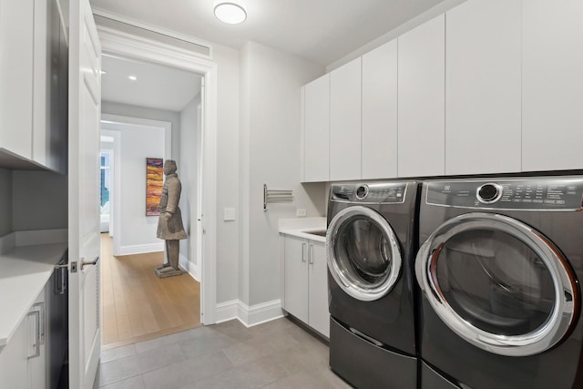 clothes washing area with light tile patterned floors, cabinets, and independent washer and dryer