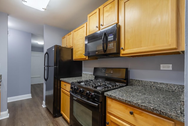 kitchen with black appliances, light brown cabinets, dark stone countertops, and dark wood-type flooring