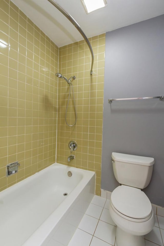 bathroom with tile patterned flooring, tiled shower / bath combo, and toilet