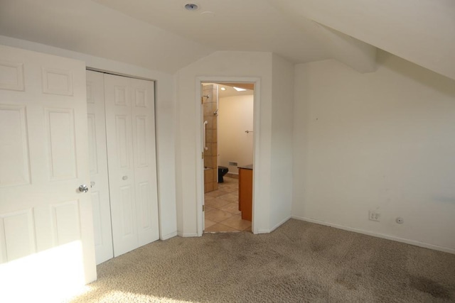 unfurnished bedroom with vaulted ceiling, light colored carpet, and a closet