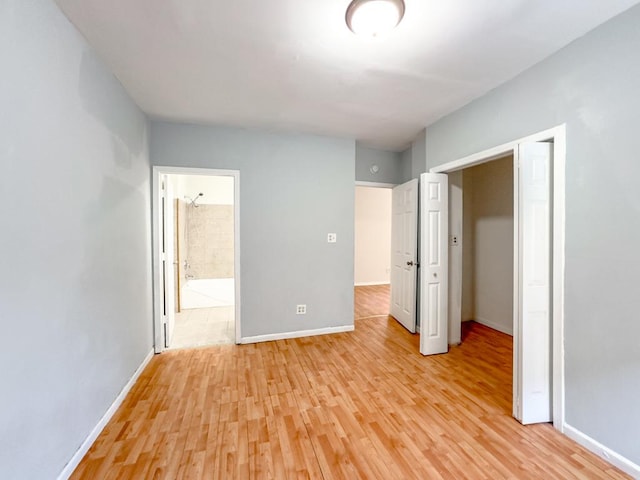 unfurnished bedroom with connected bathroom, a closet, and light hardwood / wood-style flooring