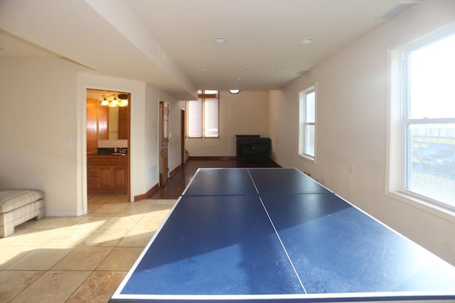 rec room with sink, light tile patterned floors, and a notable chandelier