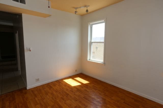 spare room featuring wood-type flooring and rail lighting