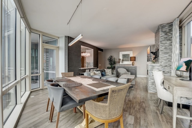 dining area featuring expansive windows, light wood-type flooring, and a notable chandelier