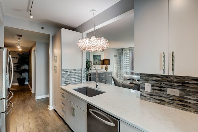 kitchen featuring sink, tasteful backsplash, pendant lighting, white cabinets, and appliances with stainless steel finishes