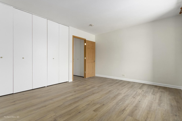 unfurnished bedroom featuring light wood-type flooring and a closet