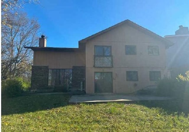 back of property with a yard and a patio