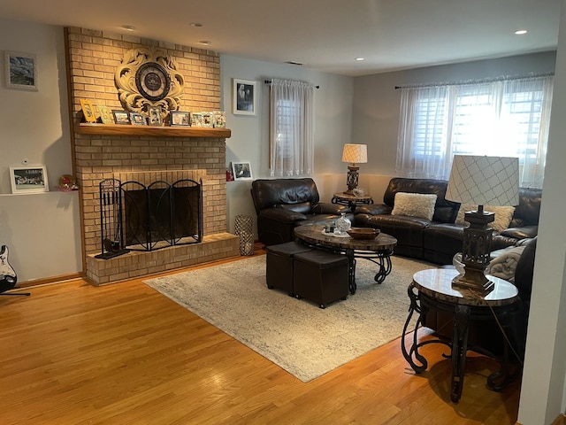 living room with a brick fireplace and hardwood / wood-style flooring