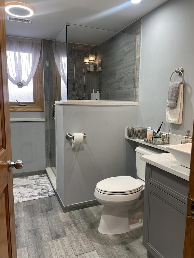 bathroom with toilet, hardwood / wood-style flooring, an enclosed shower, and vanity