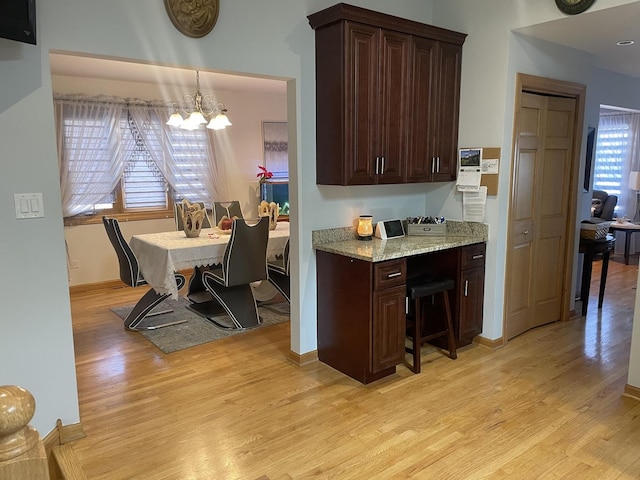 kitchen featuring hanging light fixtures, a healthy amount of sunlight, a notable chandelier, and light hardwood / wood-style flooring