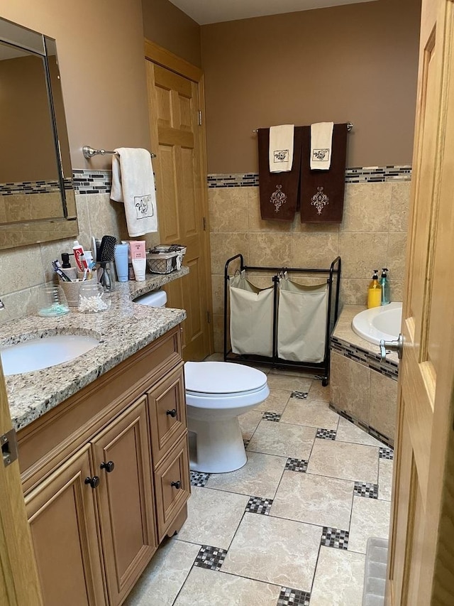 bathroom with tile patterned floors, vanity, tile walls, toilet, and a bathing tub