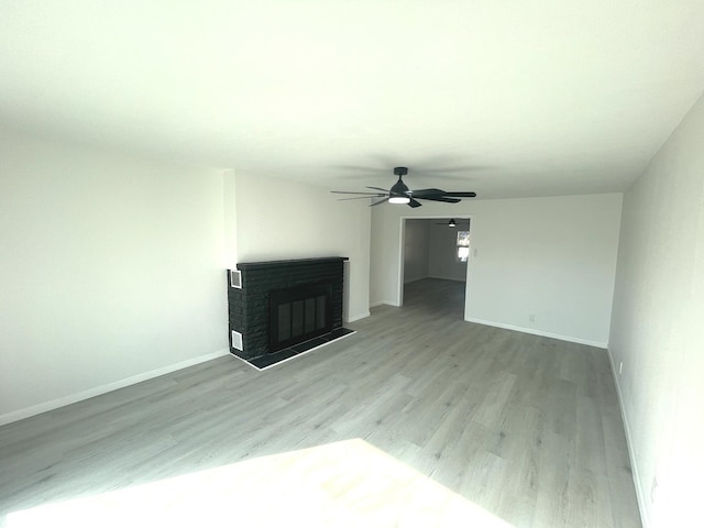 unfurnished living room with ceiling fan, light hardwood / wood-style flooring, and a brick fireplace