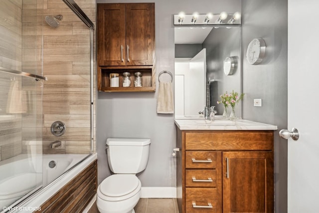 bathroom with tile patterned flooring, toilet, shower / bath combination with glass door, vanity, and baseboards