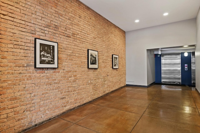 hall with recessed lighting, elevator, finished concrete flooring, and brick wall