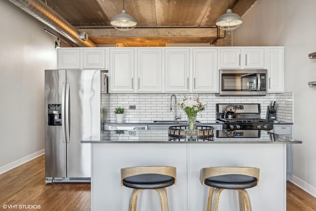 kitchen with appliances with stainless steel finishes, dark wood finished floors, white cabinets, and a sink