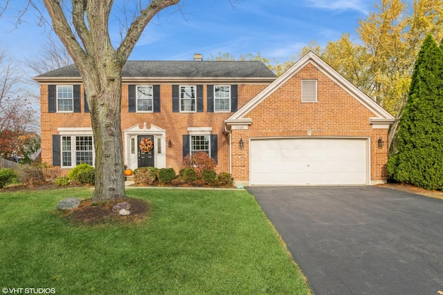 colonial-style house featuring a front yard and a garage