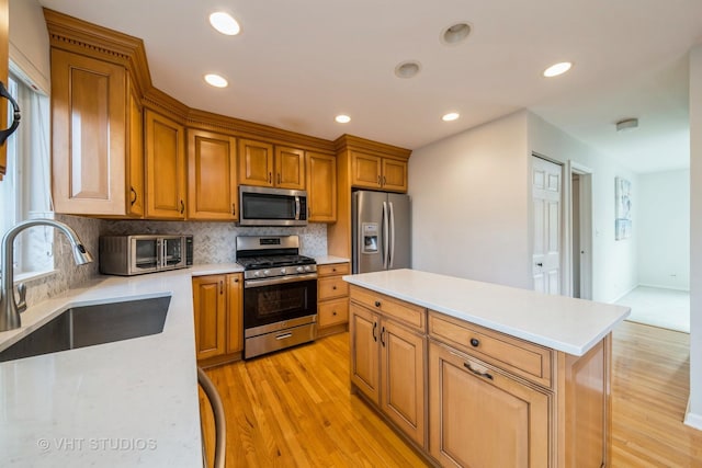 kitchen with sink, stainless steel appliances, light hardwood / wood-style flooring, decorative backsplash, and a kitchen island