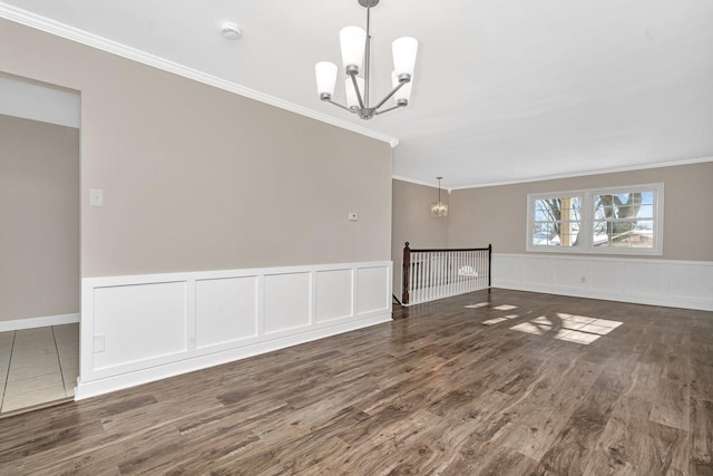 empty room featuring ornamental molding, a notable chandelier, and dark hardwood / wood-style flooring