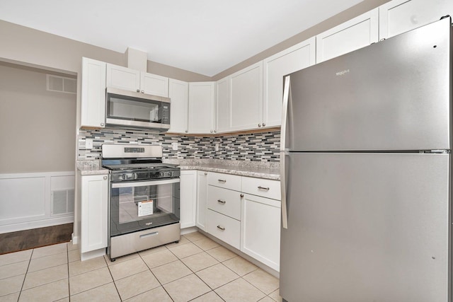 kitchen with light stone countertops, white cabinets, light tile patterned floors, and appliances with stainless steel finishes