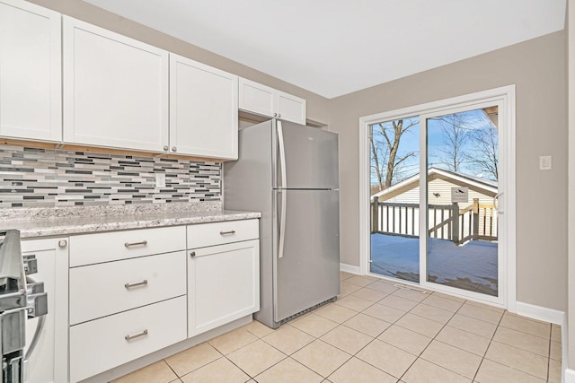 kitchen featuring stainless steel refrigerator, light tile patterned floors, light stone counters, white cabinets, and tasteful backsplash