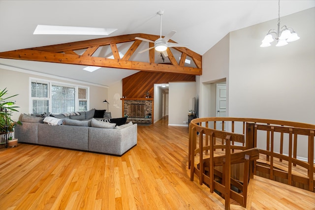 living room featuring a skylight, ceiling fan with notable chandelier, light hardwood / wood-style flooring, and high vaulted ceiling