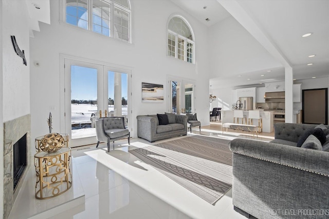 tiled living room featuring a towering ceiling, french doors, and a premium fireplace