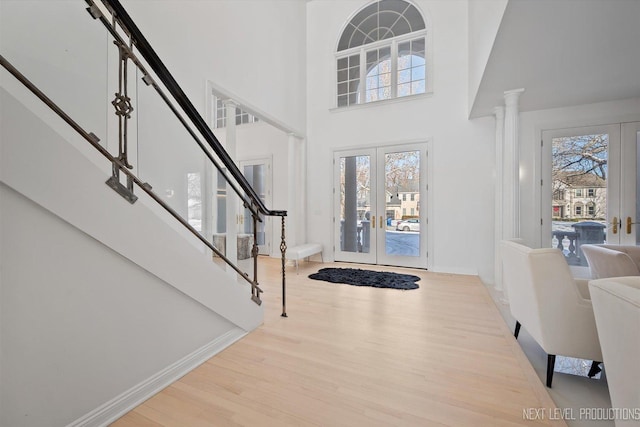 entryway featuring a high ceiling, french doors, light wood-type flooring, and a wealth of natural light