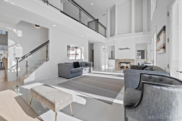 living room with a high ceiling, light wood-type flooring, and a fireplace