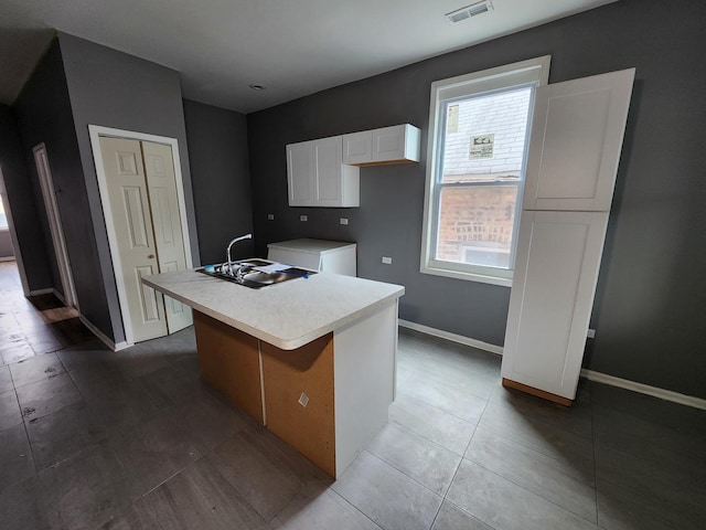 kitchen with a center island with sink, white cabinets, sink, and a wealth of natural light