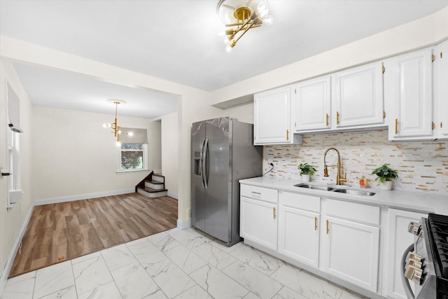 kitchen with backsplash, white cabinets, sink, appliances with stainless steel finishes, and decorative light fixtures