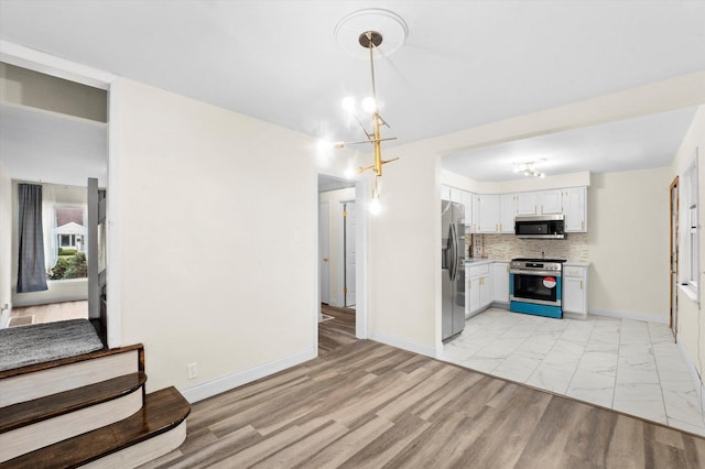 kitchen featuring tasteful backsplash, stainless steel appliances, an inviting chandelier, white cabinetry, and hanging light fixtures