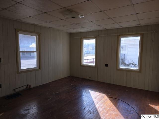 empty room with hardwood / wood-style floors and a drop ceiling